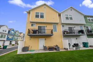 Rear view of property featuring a patio area, a residential view, board and batten siding, a lawn, and a balcony