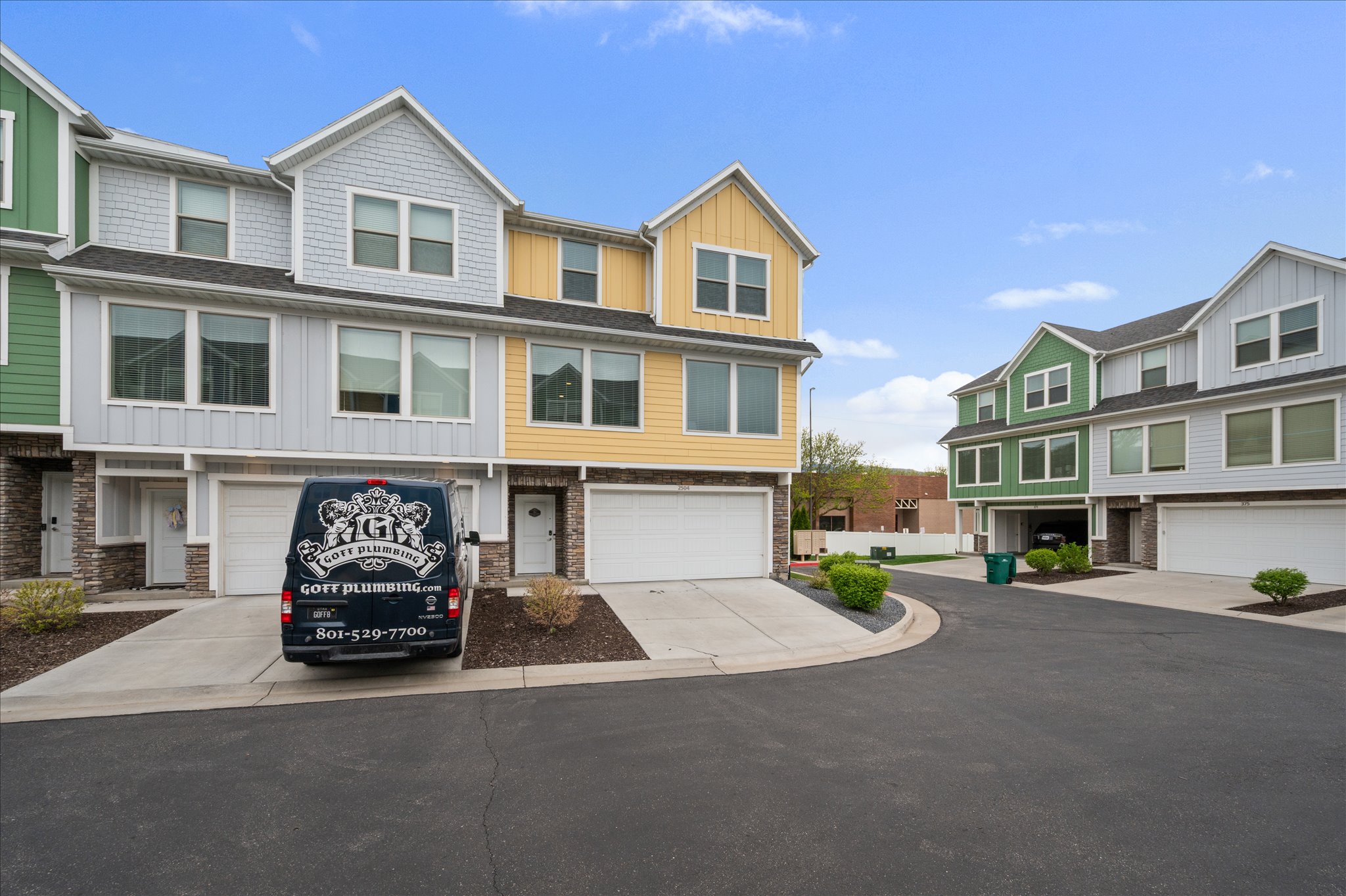 View of front facade with board and batten siding, concrete driveway, a garage, stone siding, and a residential view