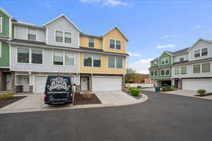 View of front facade with board and batten siding, concrete driveway, a garage, stone siding, and a residential view