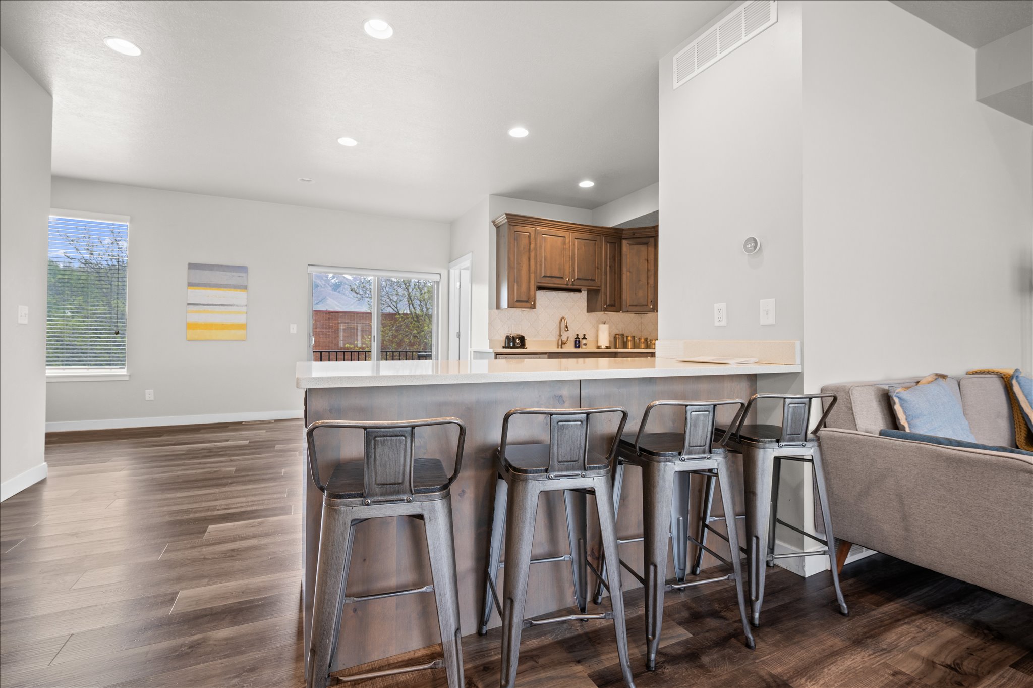 Kitchen featuring a peninsula, light countertops, open floor plan, a breakfast bar area, and dark wood-style flooring