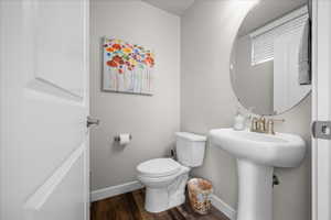 Half bathroom with toilet and dark wood-type flooring