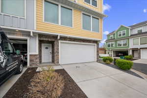 View of front of home featuring stone siding, an attached garage, driveway, and board and batten siding