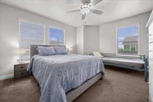 Bedroom with dark carpet, ceiling fan, and a textured ceiling