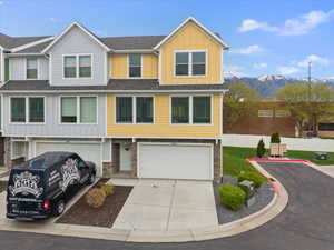 View of front of home with board and batten siding, stone siding, driveway, an attached garage, and a mountain view