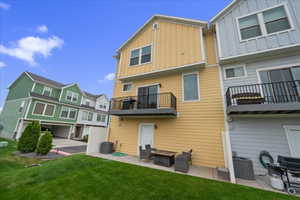 Rear view of property with board and batten siding, a patio, a balcony, a yard, and a fire pit