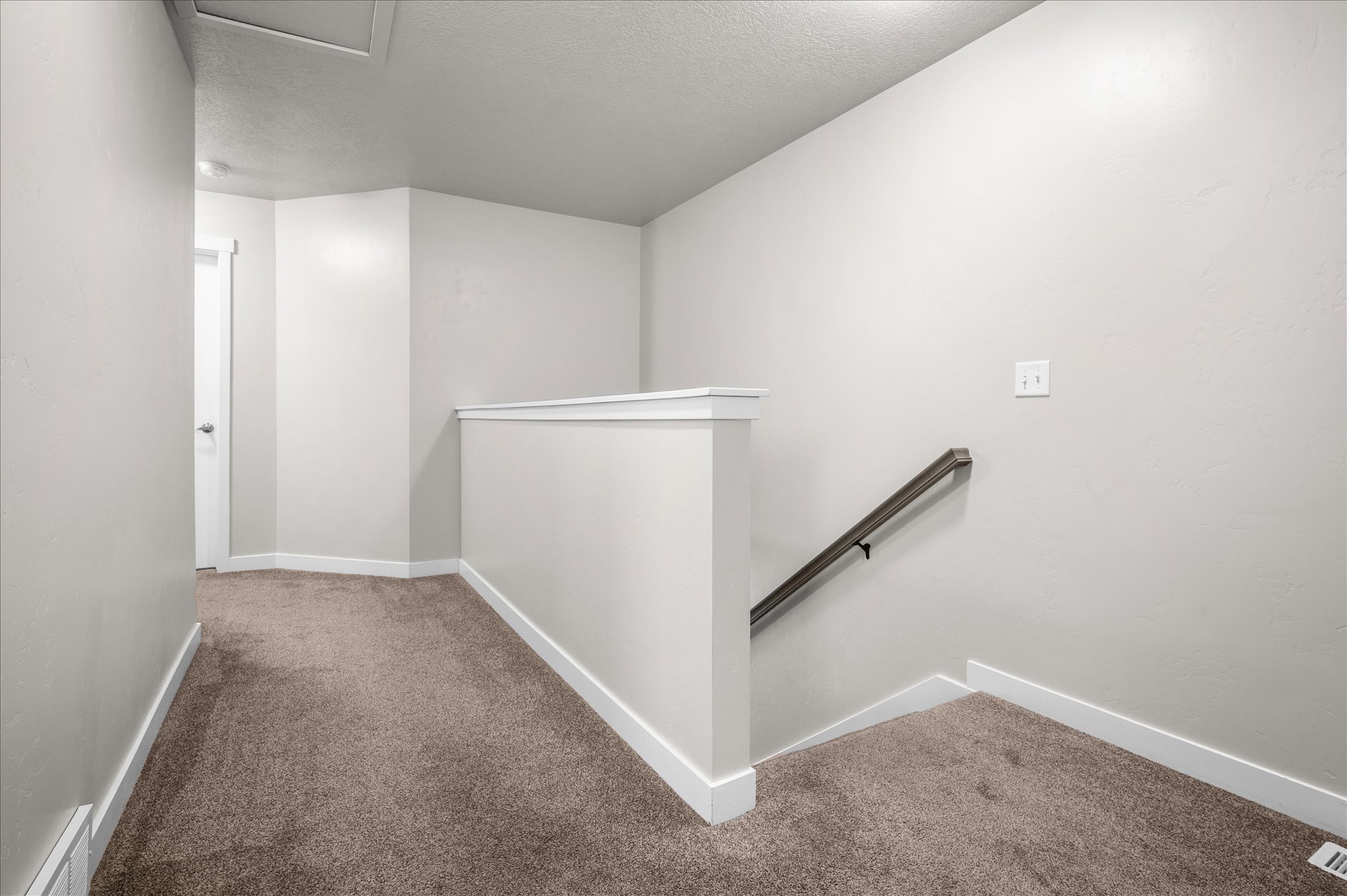 Corridor with an upstairs landing, carpet floors, and a textured ceiling