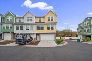 View of front facade with driveway, board and batten siding, a garage, stone siding, and a residential view