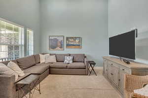 Living room with a high ceiling and light carpet