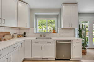 Kitchen with stainless steel dishwasher, french doors, and white cabinetry