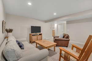 Living area with light carpet and recessed lighting