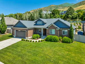 View of front of home featuring covered porch, brick siding, a garage, driveway, and a mountain view