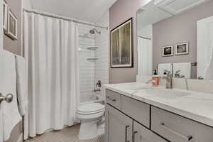 Bathroom with vanity, shower / tub combo, and light tile patterned flooring