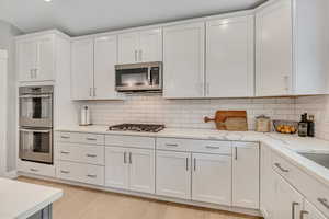 Kitchen featuring white cabinetry, stainless steel appliances, light wood-style floors, and recessed lighting