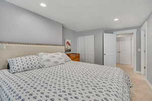 Bedroom featuring light colored carpet, recessed lighting, and a closet