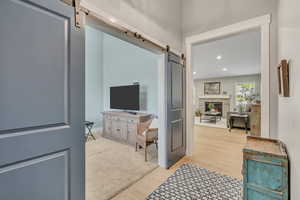 Foyer entrance featuring a barn door, recessed lighting, light wood-style flooring, and a fireplace
