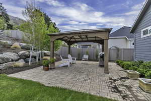 Fenced backyard featuring a gazebo, a patio area, and a grill