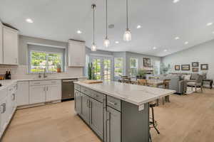 Dual tone kitchen with dual tone cabinetry, decorative backsplash, light wood finished floors, light stone counters, and lofted ceiling