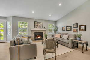 Living area featuring light wood-style floors, a fireplace, recessed lighting, and vaulted ceiling