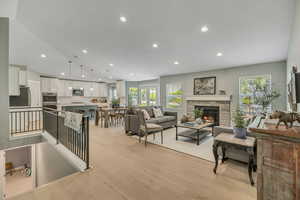 Living area with a stone fireplace, light wood finished floors, plenty of natural light, and recessed lighting