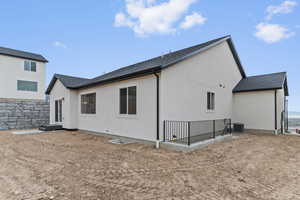 Back of property with a shingled roof and stucco siding
