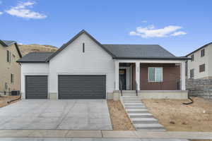 View of front of home featuring covered porch, an attached garage, driveway, and roof with shingles