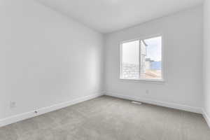Spare room with light colored carpet and baseboards