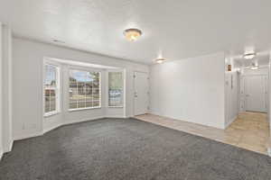 Foyer entrance with light carpet and a textured ceiling
