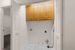 Laundry room featuring gas dryer hookup, cabinet space, hookup for a washing machine, and light tile patterned floors