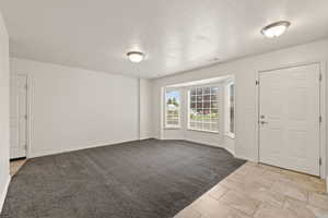 Entrance foyer featuring a textured ceiling and light colored carpet