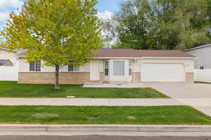 View of front of home with an attached garage, driveway, and brick siding