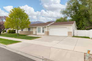 Single story home with a gate, concrete driveway, brick siding, and a garage