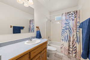 Bathroom with vanity, shower / bath combination with curtain, and light tile patterned floors