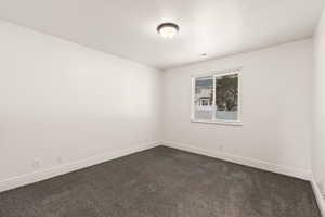 Unfurnished room with dark colored carpet and a textured ceiling