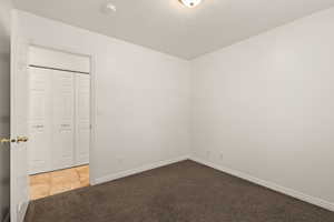 Unfurnished bedroom with dark colored carpet and a textured ceiling