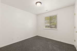 Unfurnished room with a textured ceiling and dark carpet