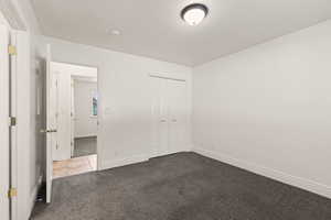 Unfurnished bedroom with light colored carpet, a closet, and a textured ceiling