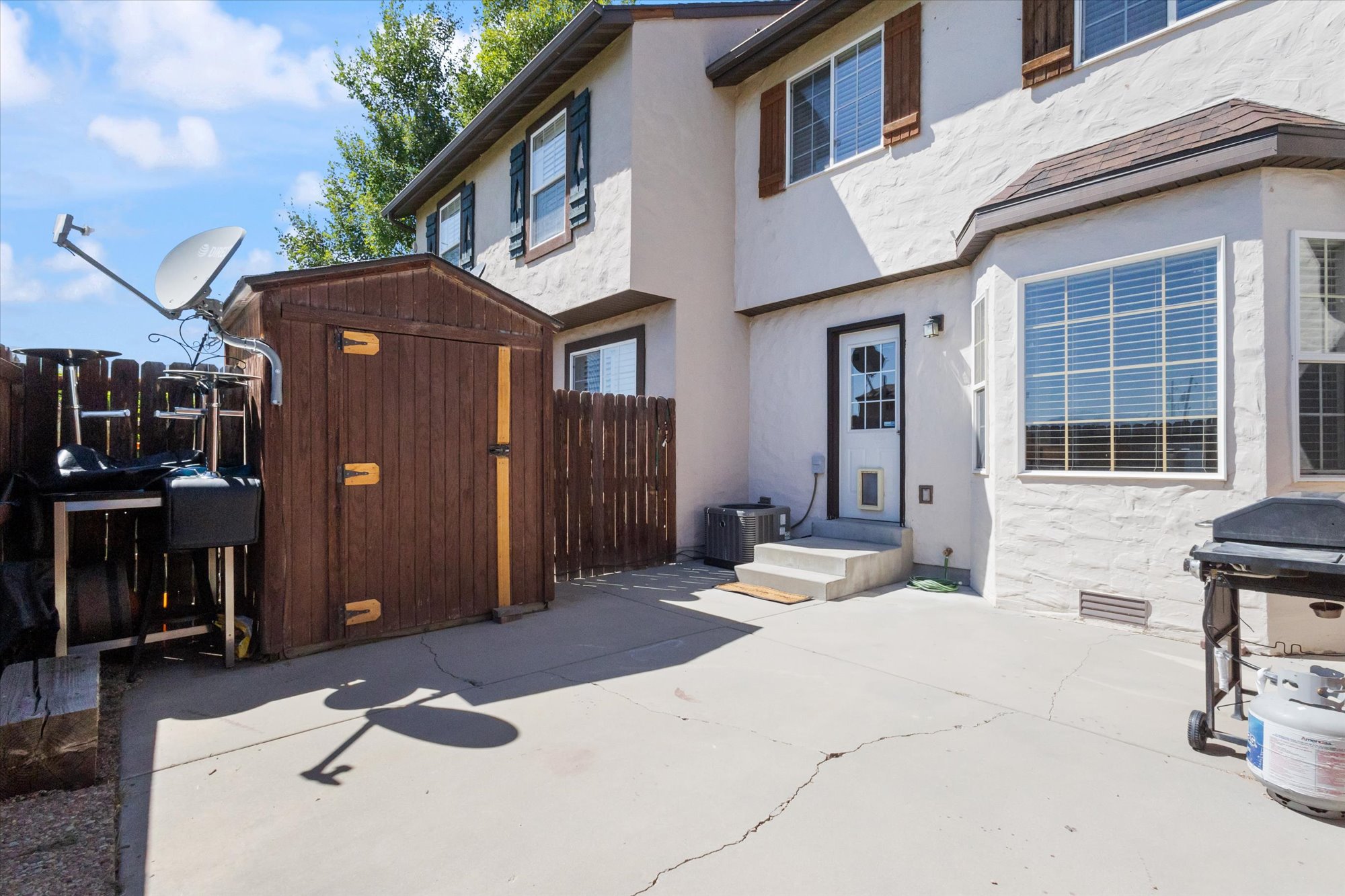 Rear view of house with a patio, a storage unit, and stucco siding