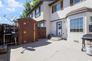 Rear view of house with a patio, a storage unit, and stucco siding