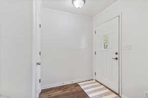 Foyer entrance featuring dark wood-type flooring, crown molding, and a textured ceiling