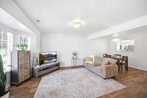 Living area featuring crown molding, dark wood-style flooring, and a textured ceiling