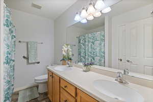 Full bath with double vanity and a shower with shower curtain