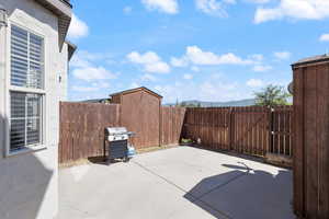 Fenced backyard with a gate, a patio, a grill, and a mountain view