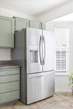 Kitchen featuring stainless steel fridge, green cabinetry, dark countertops, and a textured ceiling