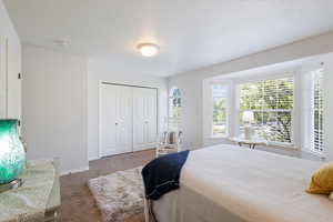 Carpeted bedroom with a textured ceiling and a closet