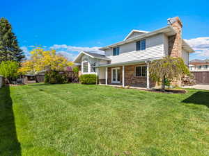 Back of property featuring a chimney, brick siding, a fenced backyard, and french doors