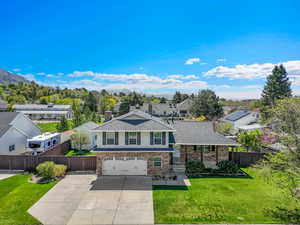 View of front facade with an attached garage, driveway, brick siding, and roof with shingles