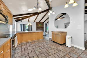 Kitchen with hanging lights, stainless steel appliances, a peninsula, light countertops, and vaulted ceiling with beams
