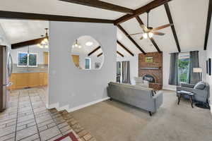 Living area with a ceiling fan, a brick fireplace, beamed ceiling, light colored carpet, and hanging lights