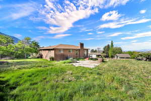 Rear view of house with a patio, a mountain view, brick siding, and a chimney