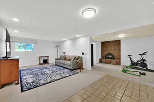 Living area with light colored carpet, a brick fireplace, a textured ceiling, light tile patterned flooring, and recessed lighting